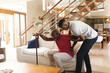 © Wavebreak Media - African american young man helping his father with back pain to get up from the couch at home