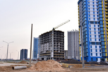 Facade of a new modern high-rise residential building. Tower crane on construction of a residential building. Cranes on formworks. Realtor and Real Estate. Construction the building