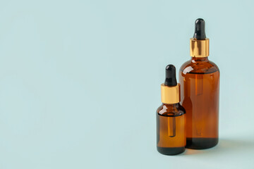 Two bottles with natural serum or oil on the blue background. Self care with organic handmade cosmetics.