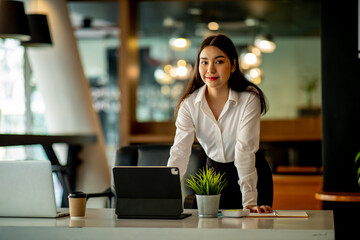 Portrait of Asian young female Businesswoman working on laptop computer doing finances,accounting analysis,report,data and pointing graph at the office.