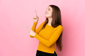 Wall Mural - Young caucasian woman isolated on pink background pointing with the index finger a great idea