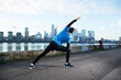 UK, London, Jogger stretching with downtown skyline in background