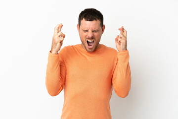 Brazilian man over isolated white background with fingers crossing