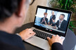 © alex.pin - Computer portatile nel cui schermo compaiono tre persone in remoto in videoconferenza con un uomo seduto davanti al computer