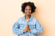 © luismolinero - Young African American woman isolated on beige background keeps palm together. Person asks for something