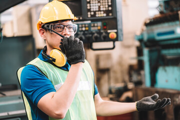 work at factory.asian worker man working in safety work wear with yellow helmet and glasses l ear mu