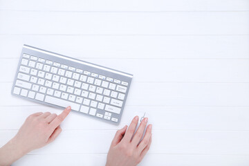 Wall Mural - Female hands typing on computer keyboard and holding mouse on white background