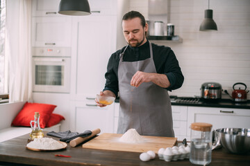 A male chef prepares dough at home in the kitchen