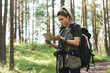 Female hiker with big backpack using map for orienteering in the forest