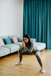 © shevtsovy - Young sporty woman doing squat morning exercise. home fitness routine. Woman with strong glutes workout at home. Female gymnastics. Butt workout motivation.