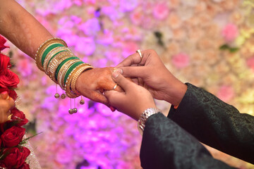 Closeup of the groom putting a ring on the bride's finger in the ceremony