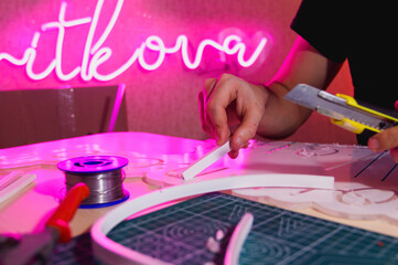 Wall Mural - Cropped view of craftsman holding stationery knife near flex neon in workshop 