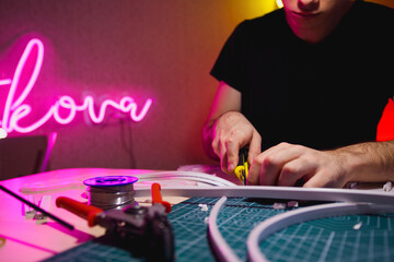 Wall Mural - Cropped view of craftsman cutting flex neon stripe in workshop 