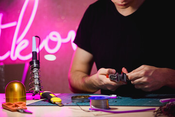 Wall Mural - Craftsman holding wire cutters near neon stripe and soldering iron in workshop 