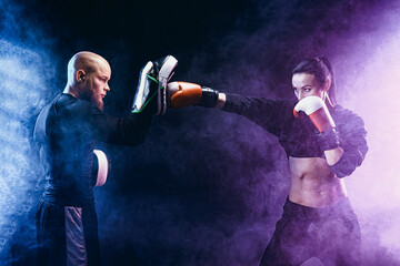 Wall Mural - Woman exercising with trainer at boxing and self defense lesson