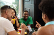 © etonastenka - Young black man showing something on the phone screen to his friends while sitting in a cafe