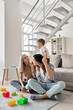 © insta_photos - Happy young family with kid playing enjoying time together at home in living room, parents with child sitting talking on floor near sofa, dad holding boy on shoulders, mom smiling looking at kid.