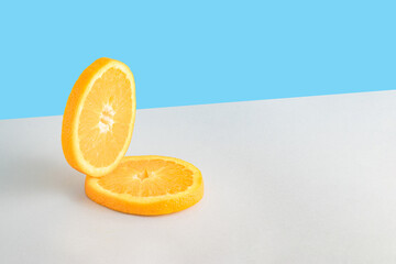 Creative summer composition with two slices of fresh orange on a blue and gray background. Minimal fresh nature or food concept.