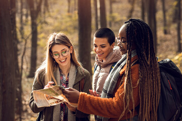 three female friends having fun and enjoying hiking in forest.