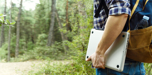 Young man holding laptop at the forest