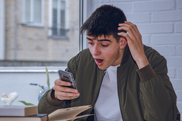 Wall Mural - surprised student looking at the mobile phone