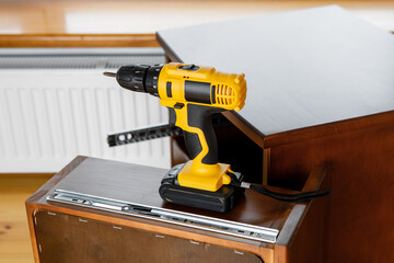 yellow screwdriver on a wooden table. power drill