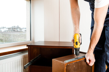 Handyman in blue uniform works with electricity automatic screwdriver. House renovation conception.