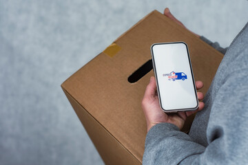 Express delivery in your phone. A man holds a smartphone with an icon on a white screen in his hands.