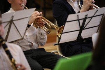 Wall Mural - School band rehearsal. Students boys in a white shirt sitting playing a musical instrument trumpet clarinet on the notes.Close-up image