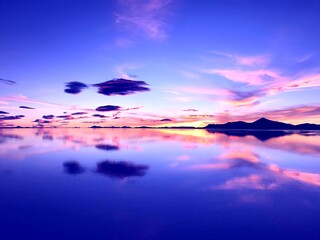 Wall Mural - Sunset over lake. Wonderful sunset in mountains. Surreal natural landscape at salt flat Salar de Uyuni. Bright colors of desert. Incredible sky clouds reflection in calm water. Magical alien nature.