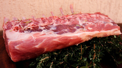 Carré de Cordeiro. Raw rack of lamb. Spiced with rosemary and herbs on black background