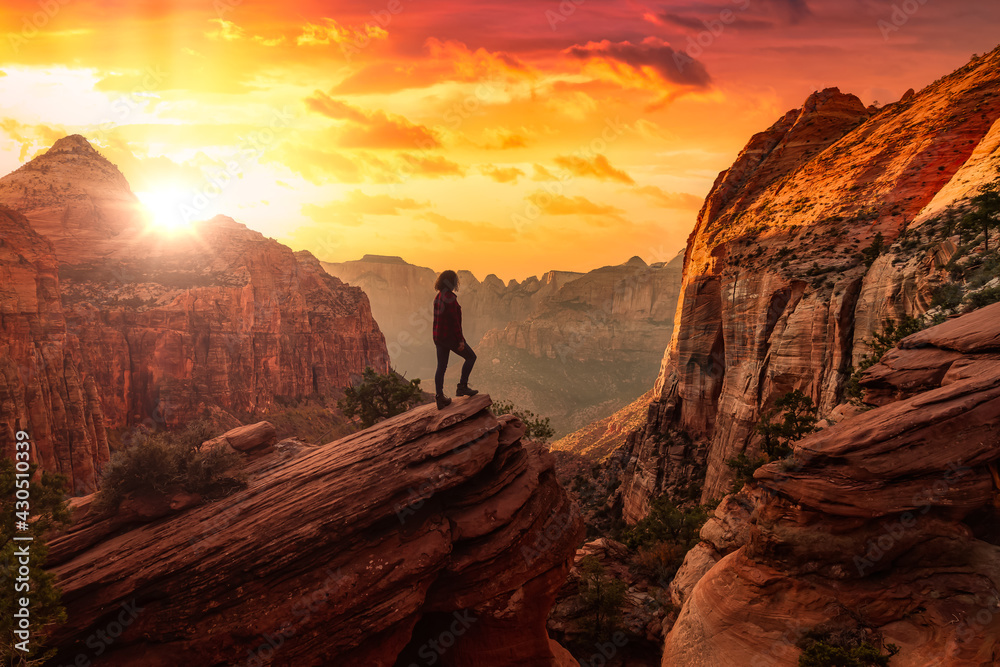 Adventurous Woman at the edge of a cliff is looking at a beautiful ...