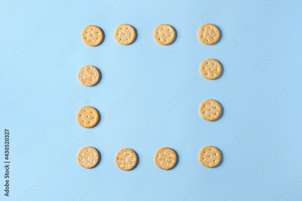 Frame made of tasty crackers on color background