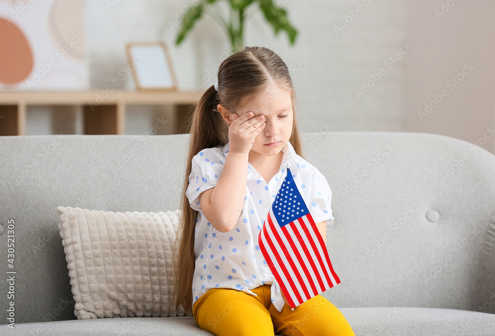 Sad little girl with USA flag at home. Memorial Day celebration