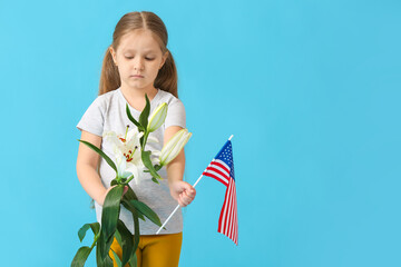 Little girl with USA flag and flowers on color background. Memorial Day celebration