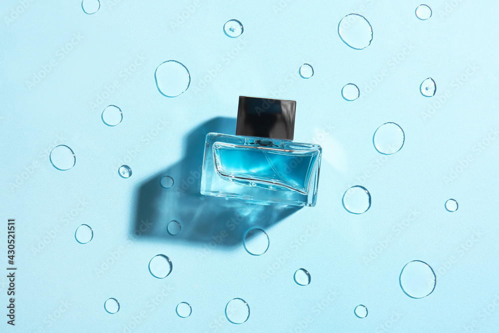 Bottle of perfume on color background with water drops