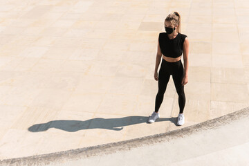 Athletic woman wearing face mask during summer street workout