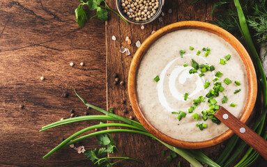 Creamy Mushroom Soup with croutons, spices and chives on rustic wooden table background