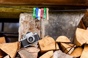 old film camera laying on a firewoods near rural house, natural background. hobbies and leisure concept. horizontal close up photo