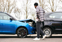 Young Male Driver Getting Out Of Car And Inspecting Damage After Road Traffic Accident