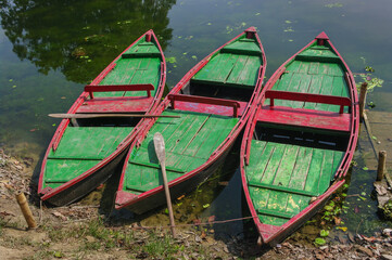 Poster - Colorful red and green recreational wooden boats with oar on a lake in Sonargaon, Bangladesh