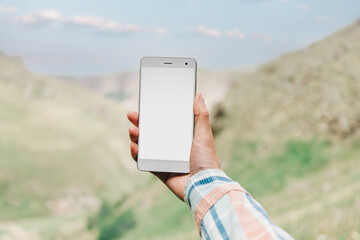 Sticker - Mockup image of a woman holding mobile phone with blank desktop screen in mountain background.