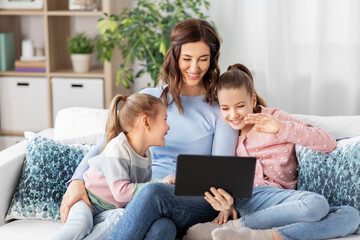 Poster - people, family and technology concept - happy mother and two daughters with tablet pc computer having video call at home