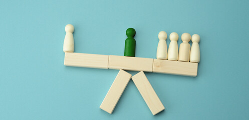 wooden figures of men on a swing, between them a negotiator. The concept of negotiations, reconciliation of parties