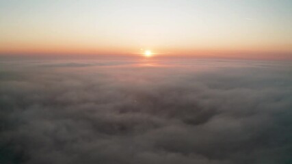 Wall Mural - Aerial video over а morning calm sea covered with low clouds and beautiful sunrise