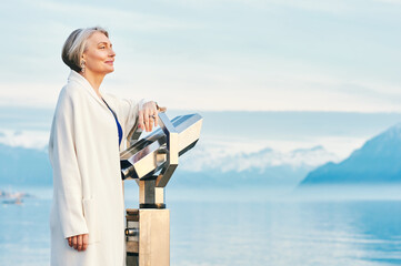 Beautiful middle age woman admiring amazing view of winter lake and mountains