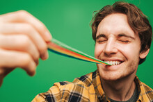 Young Man Eats Jelly Candy With Pleasure, Isolated On Green Background