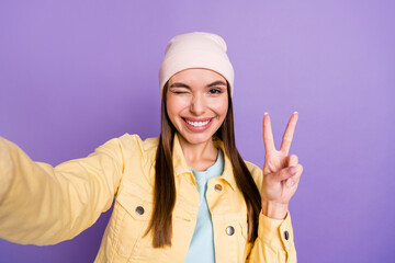 Sticker - Photo portrait of smiling girl taking selfie in casual clothes showing v-sign gesture winking isolated on pastel violet color background