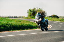Motorcycle Driver Riding Alone On The Asphalt Road. Lifestyle Photo Of A Biker In The Motion At The Empty Road