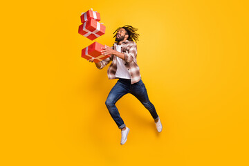 Full length body size view of nice cheerful guy jumping throw drop falling giftboxes isolated over bright yellow color background